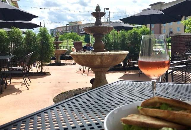 Outdoor patio with fountain, rosé, and sandwich plate—featured in 15317 Lifestyle Publication.